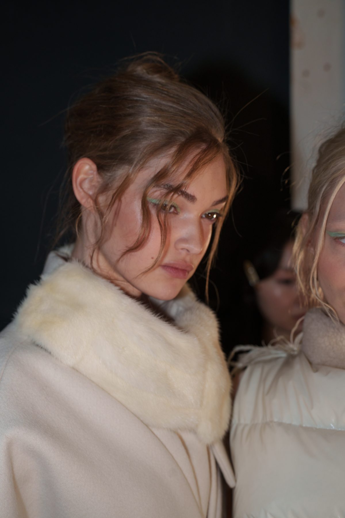 Backstage beauty close-up with sleek bun and mint eye makeup, New York Fashion Week